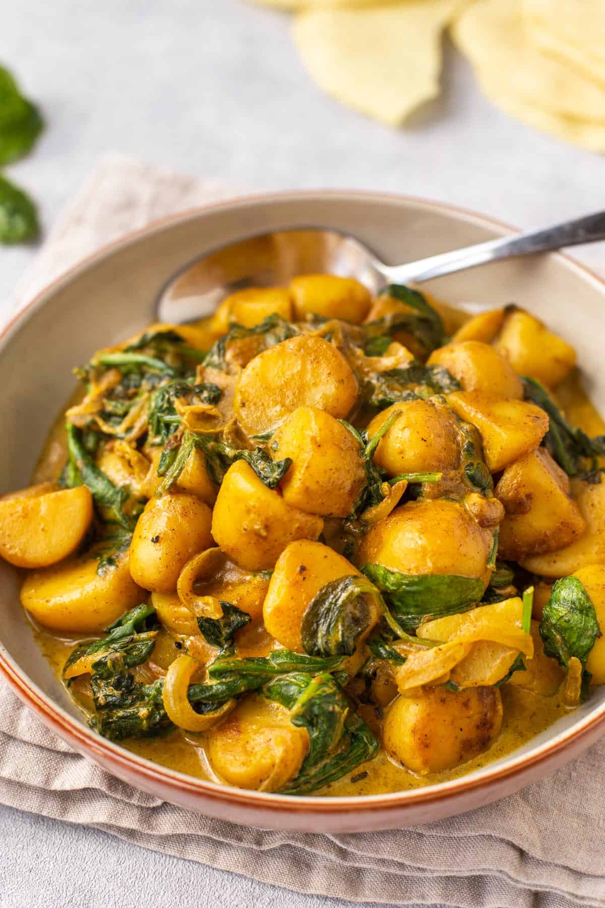 Saag aloo in a bowl with a spoon.