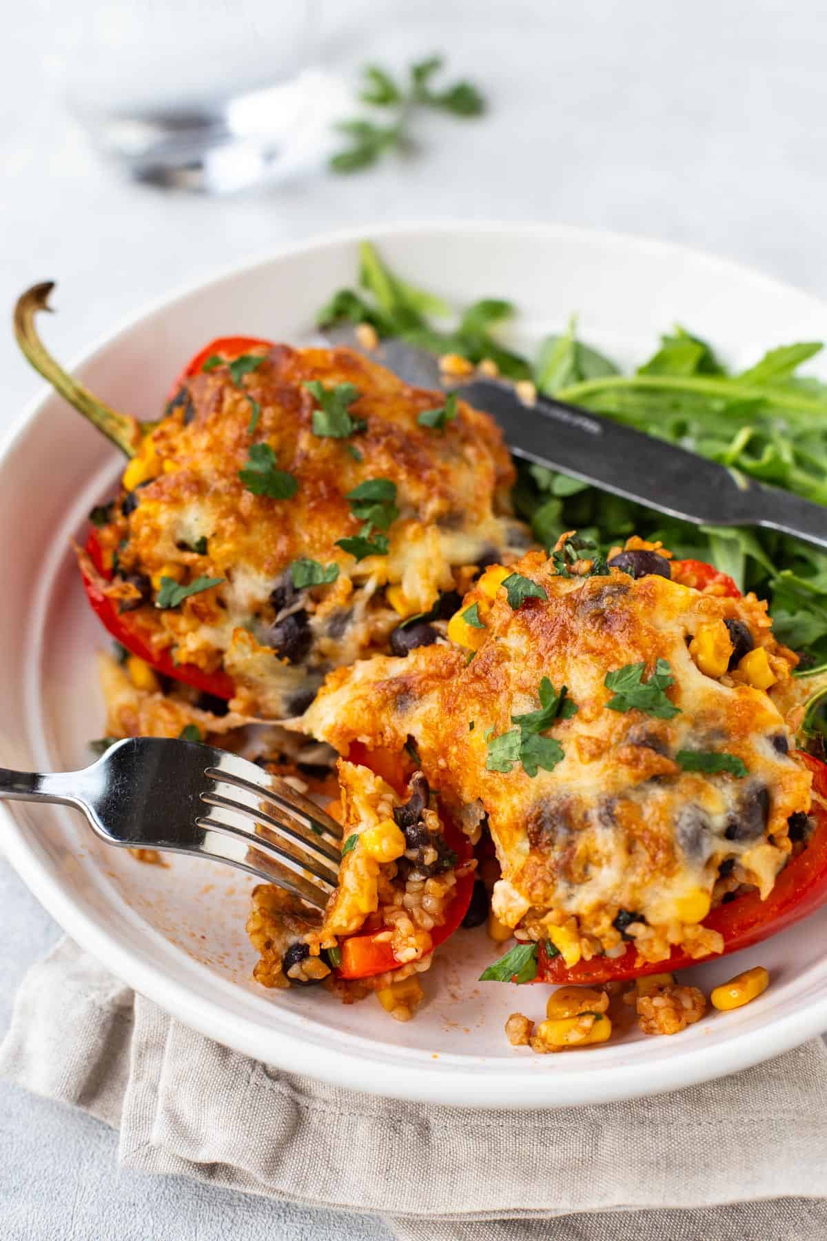 A fork cutting into a vegetarian stuffed pepper with crispy cheese topping.