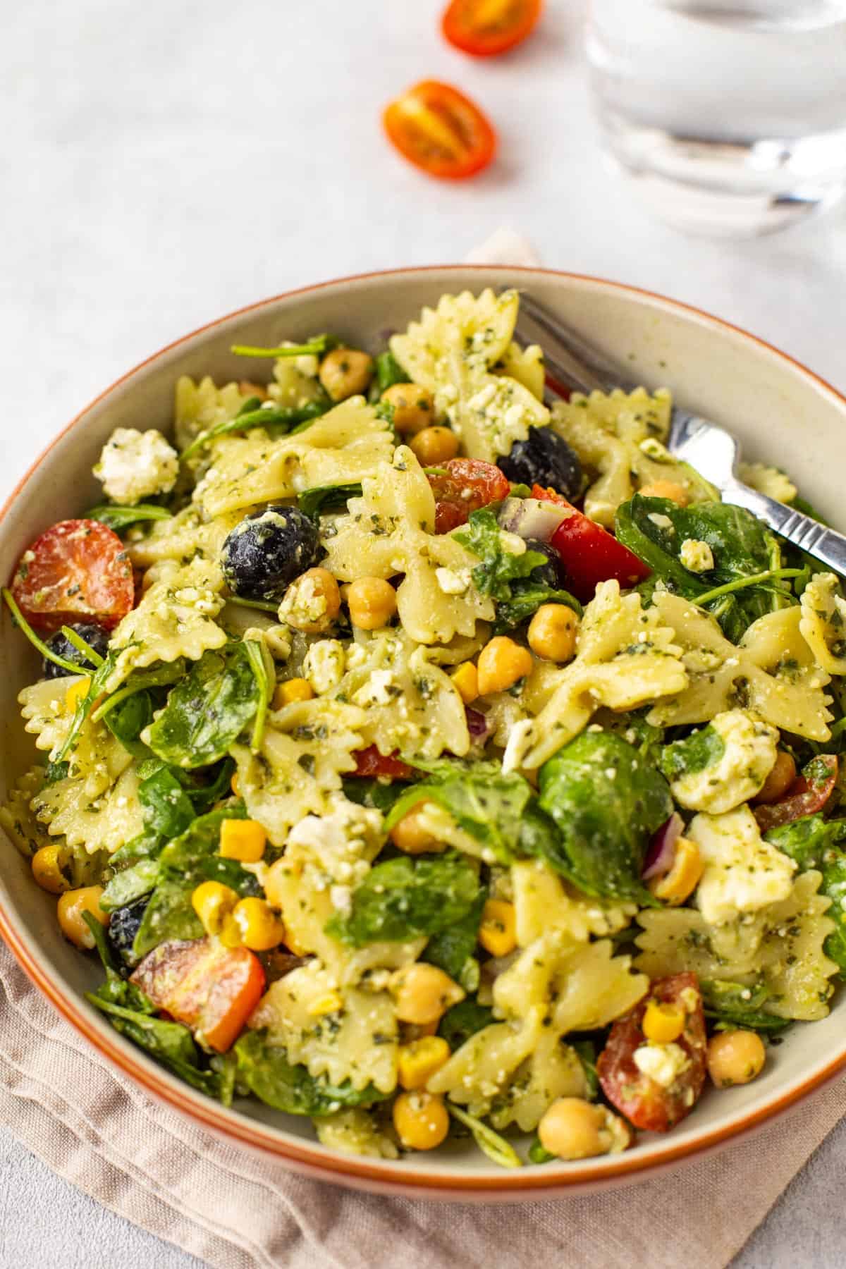 A bowlful of vegetarian chickpea pasta salad with feta cheese and tomatoes.