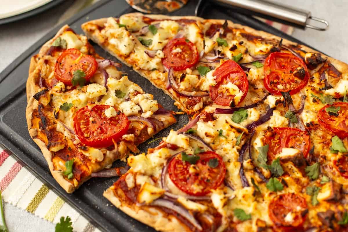 Indian pizza with tomatoes and paneer on a naan crust.
