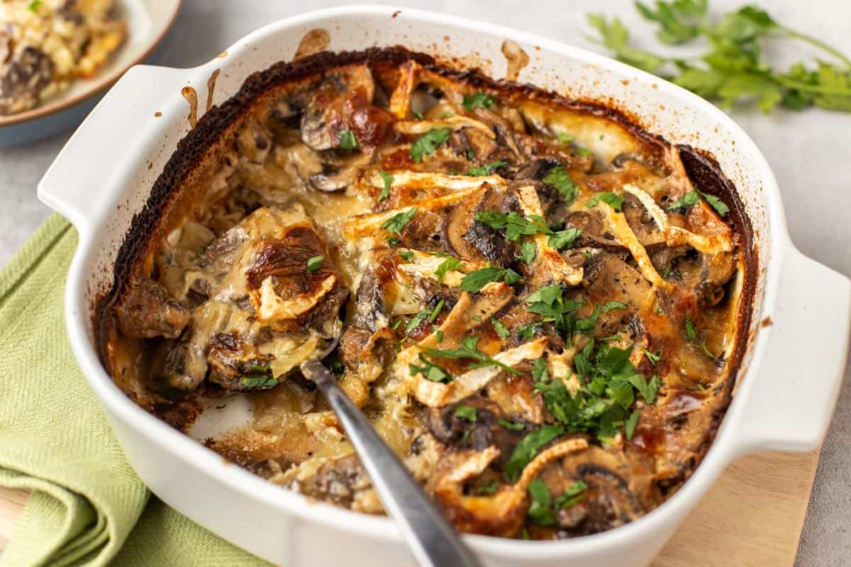 Potato and mushroom bake in a dish topped with crispy brie.