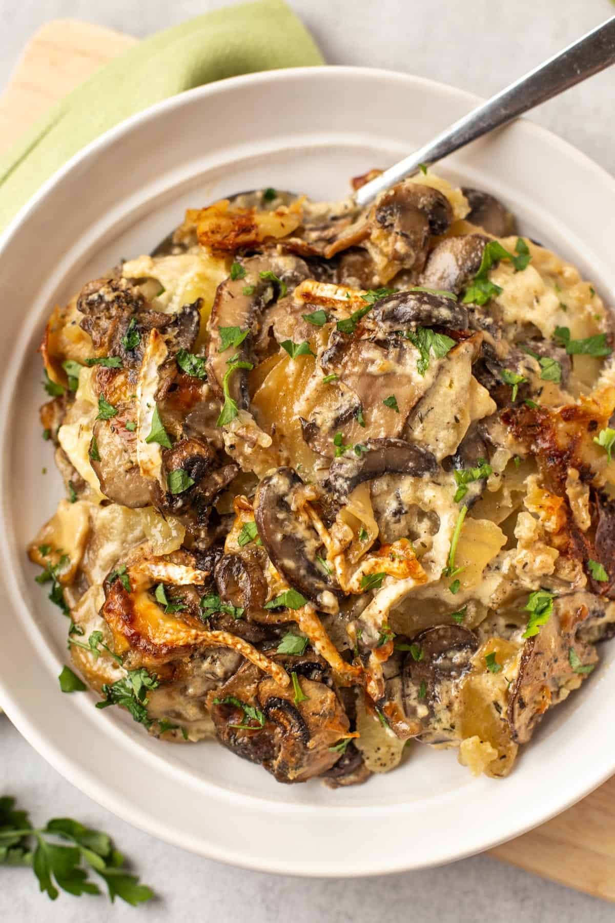 Mushroom and potato gratin in a bowl topped with fresh parsley.