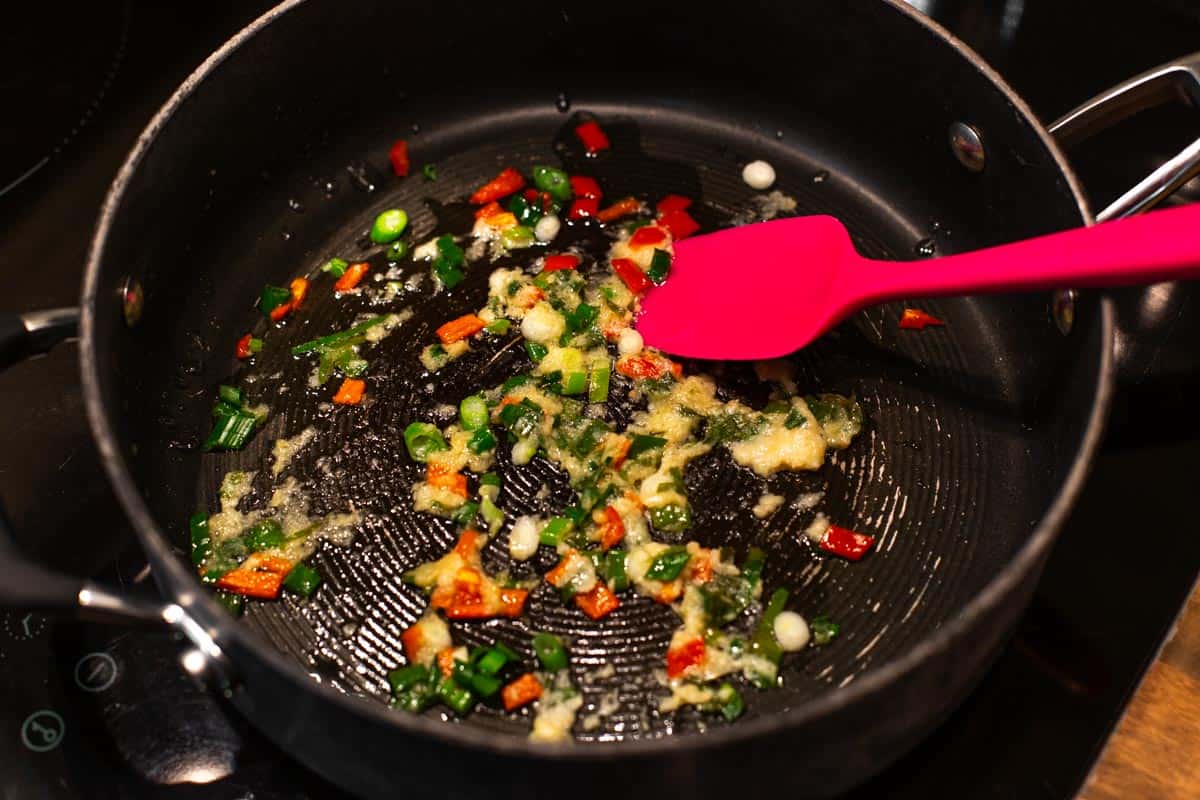 Garlic, spring onion and chilli cooking in a pan.