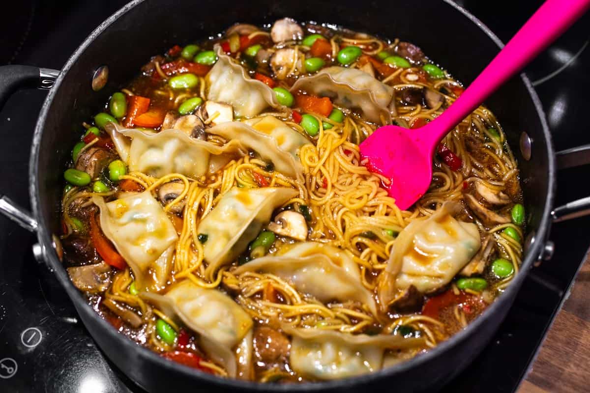 Vegetarian gyoza soup with noodles in a pan.