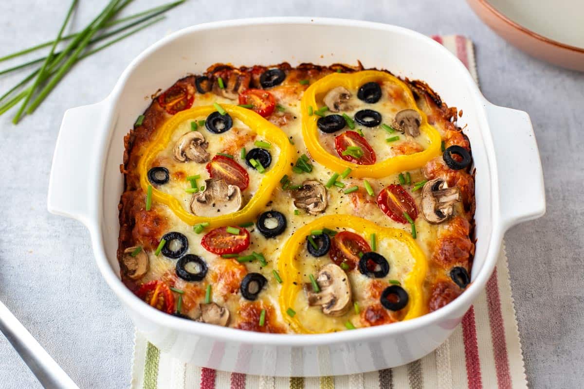 Cheesy pizza baked gnocchi topped with vegetables.