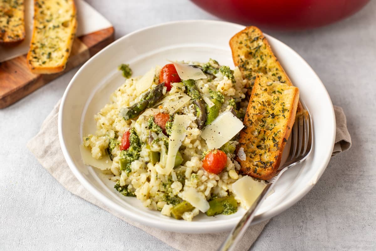 A portion of asparagus risotto with garlic bread and cheese.