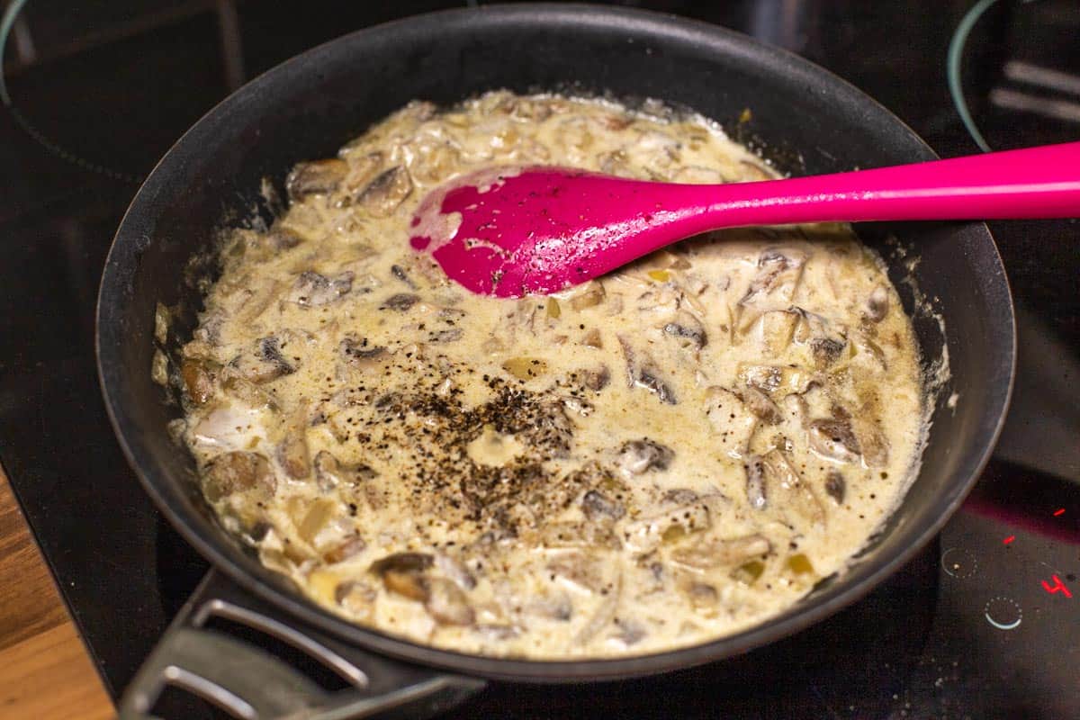 Creamy mushroom and white wine sauce cooking in a frying pan.