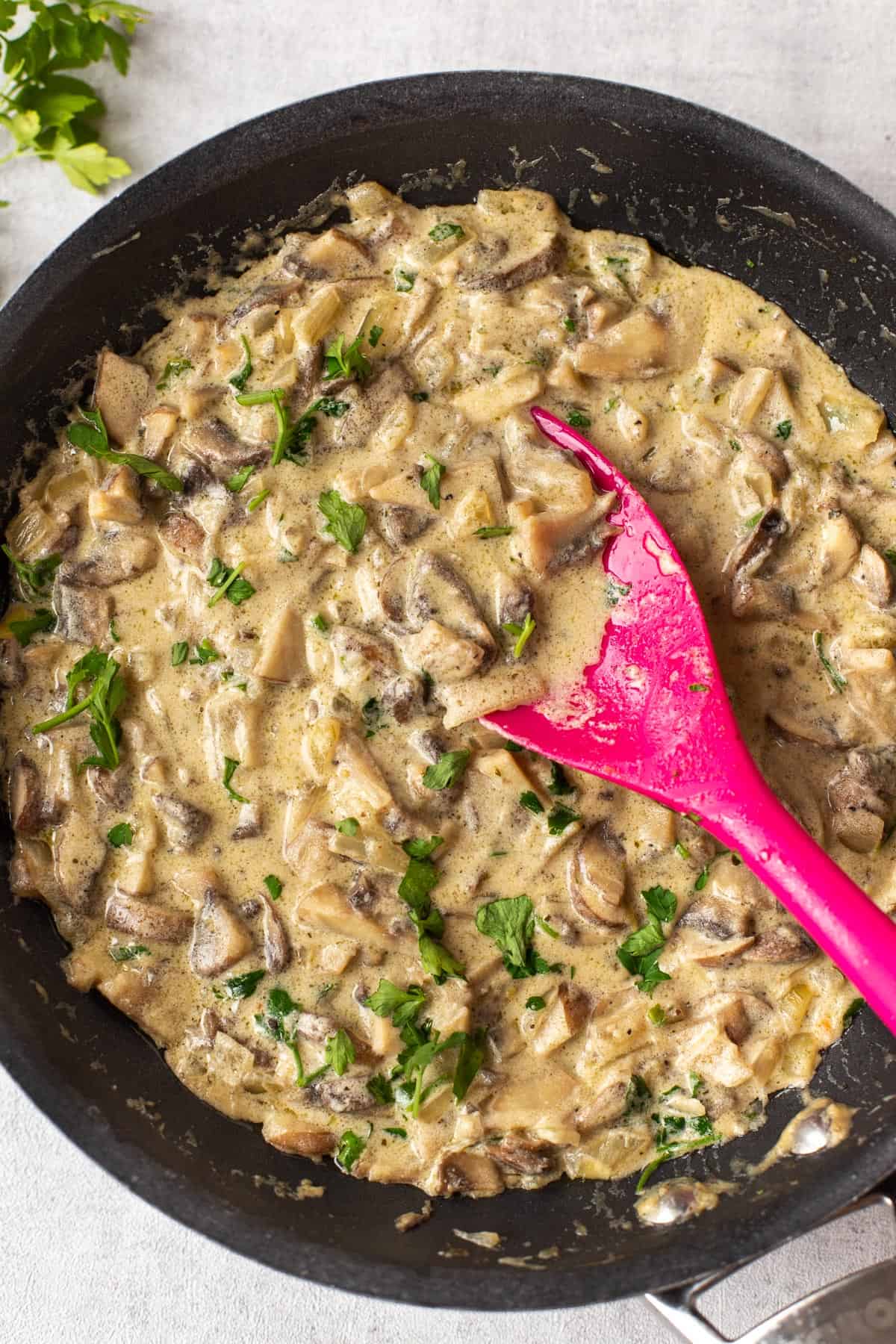 A frying pan with creamy mushroom and white wine sauce topped with parsley.