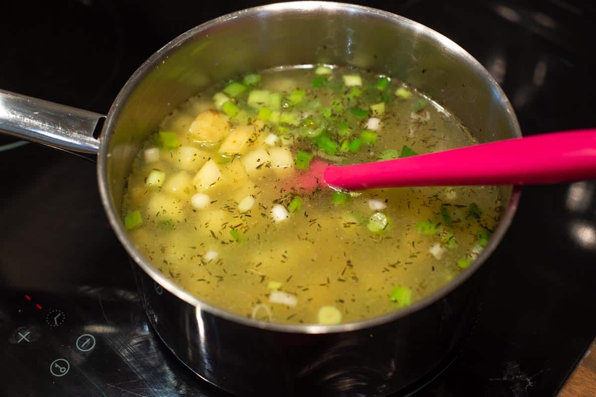 Diced potatoes, spring onions and vegetable stock in a saucepan.