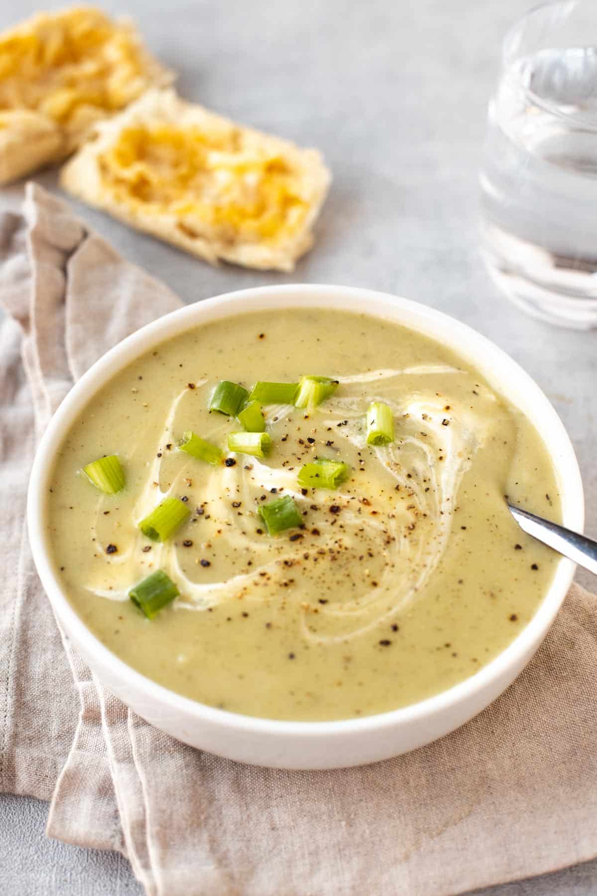 A bowlful of creamy potato and spring onion soup drizzled with cream.
