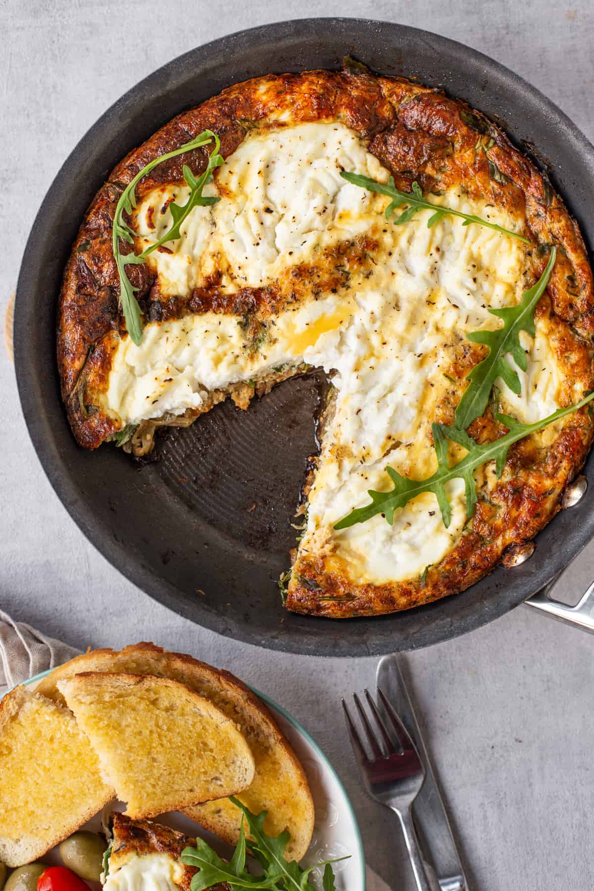 A vegetarian onion and ricotta frittata in a pan with a slice removed.