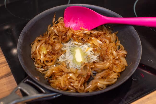 Caramelised onions in a frying pan with melted butter.