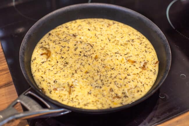 Uncooked caramelised onion frittata in a pan.