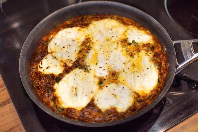 Caramelised onion and ricotta frittata in a frying pan.