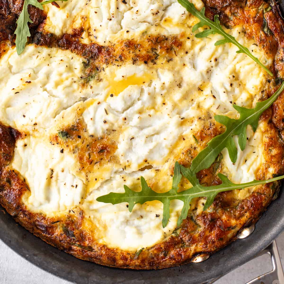 Close up shot of a caramelised onion frittata topped with creamy ricotta cheese.