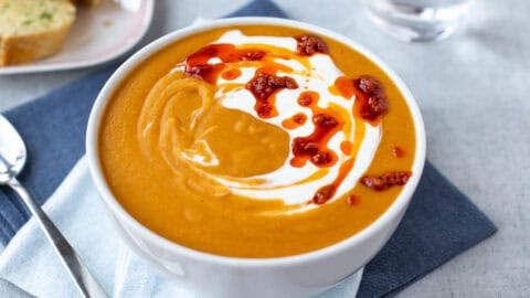 A bowl of creamy red lentil soup topped with red pesto.