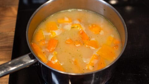 Vegetables and stock in a saucepan.