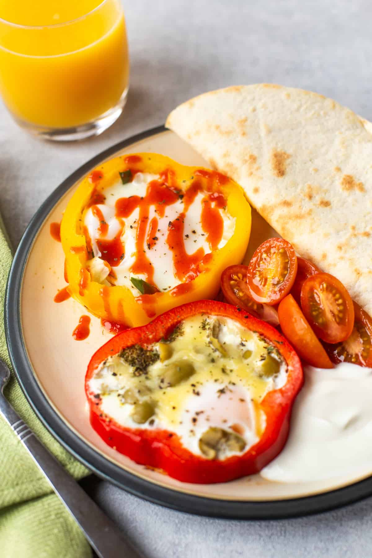 Pepper fried eggs on a plate with tomatoes and tortilla.