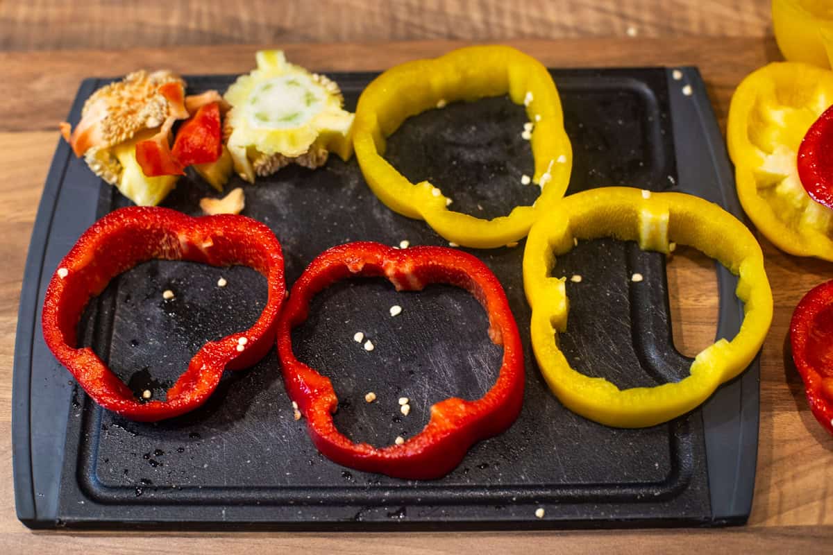 Rings of red and yellow pepper on a cutting board.