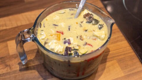 Beaten eggs with vegetables and feta mixed in.