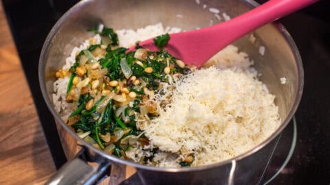 Cooked rice in a saucepan with garlic spinach and parmesan.