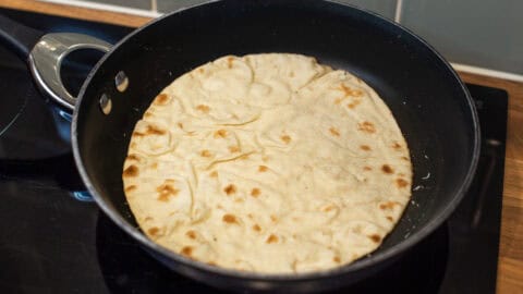 A chapatti warming through in a frying pan.