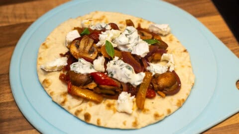 A flatbread topped with vegetables and sour cream.
