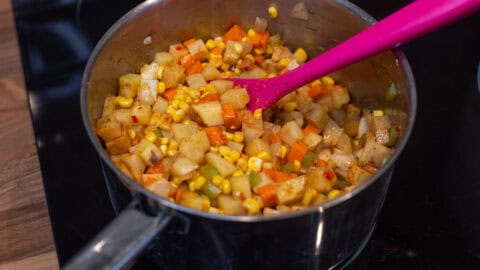 Sautéed vegetables and spices in a saucepan.