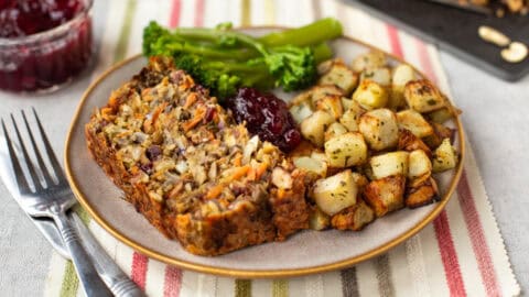 A slice of nut roast served with broccoli and potatoes.