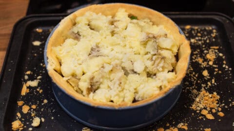 A pastry case topped with crushed potatoes.