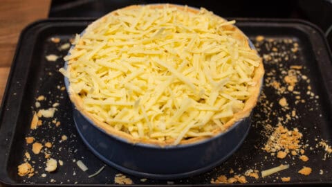 A pastry case topped with grated cheese.