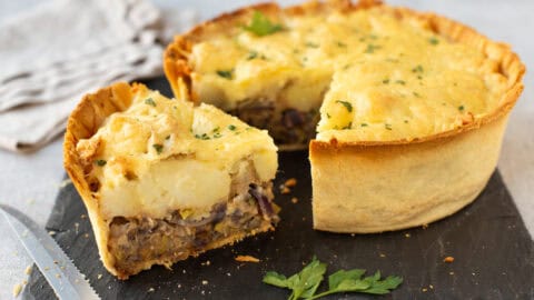 A cheesy potato and leek pie with a slice removed.