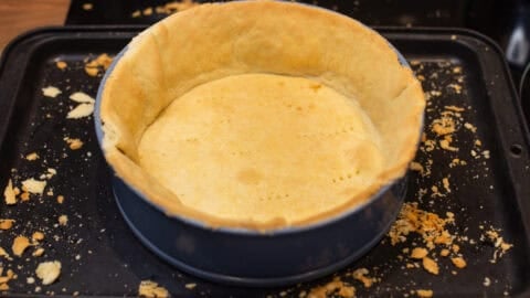 A cake tin lined with trimmed, cooked pastry.