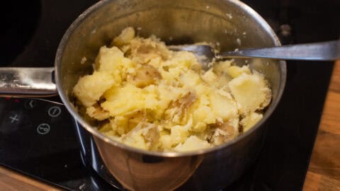 Roughly crushed boiled potatoes in a saucepan.