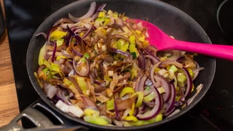 Sautéed leeks and red onion in a frying pan.