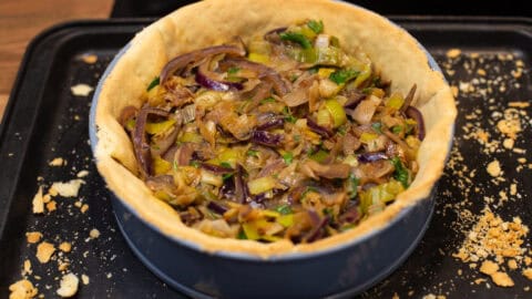 A pastry case filled with sautéed leeks and red onion.