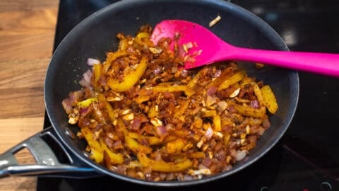 Spiced vegetables cooking in a frying pan.
