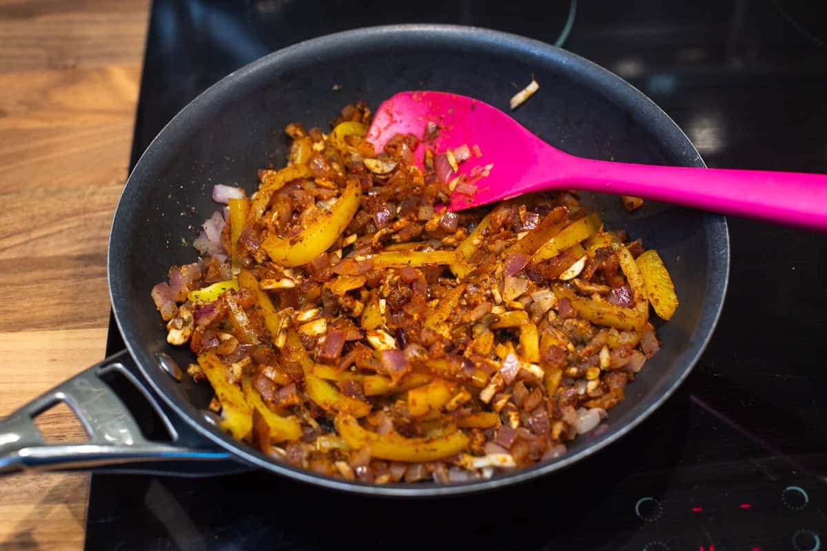 Spiced vegetables cooking in a frying pan.
