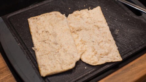 A toasted pitta bread opened on a board.