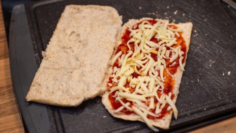 A pitta bread with tomato sauce and cheese inside.