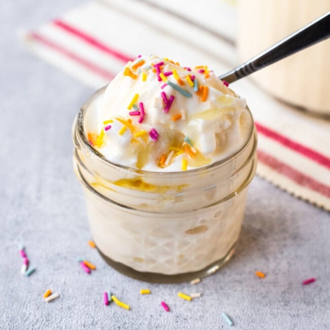 A portion of creamy cottage cheese ice cream in a bowl with sprinkles and honey.