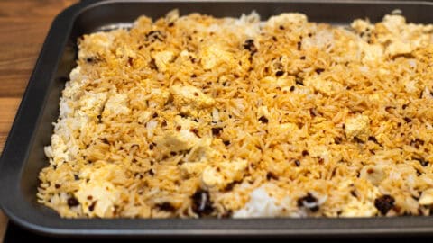 Rice and tofu spread out on a baking tray with soy sauce.