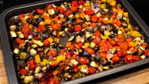 A large tray of roasted vegetables, including eggplant, tomatoes and peppers.