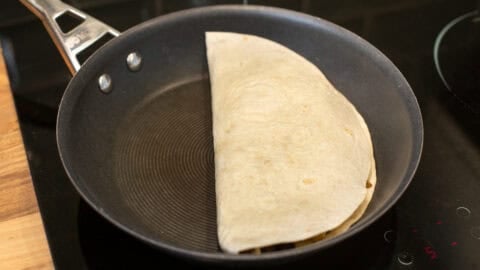 A folded tortilla in a frying pan.