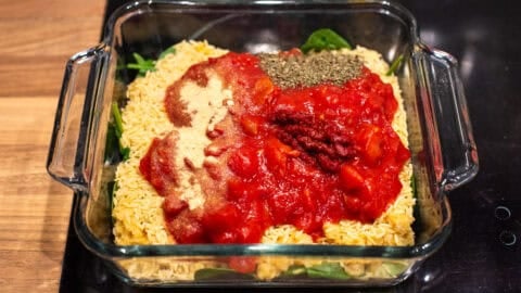 Uncooked ingredients for cheese and tomato baked orzo in a baking dish.