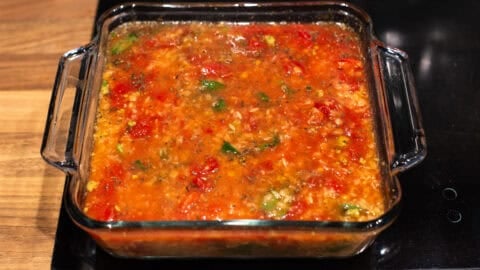 Uncooked cheese and tomato baked orzo in a baking dish.