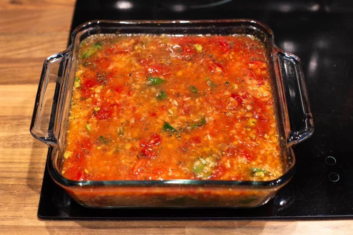Uncooked cheese and tomato baked orzo in a baking dish.