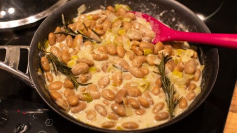 A frying pan with creamy butter beans and leeks.