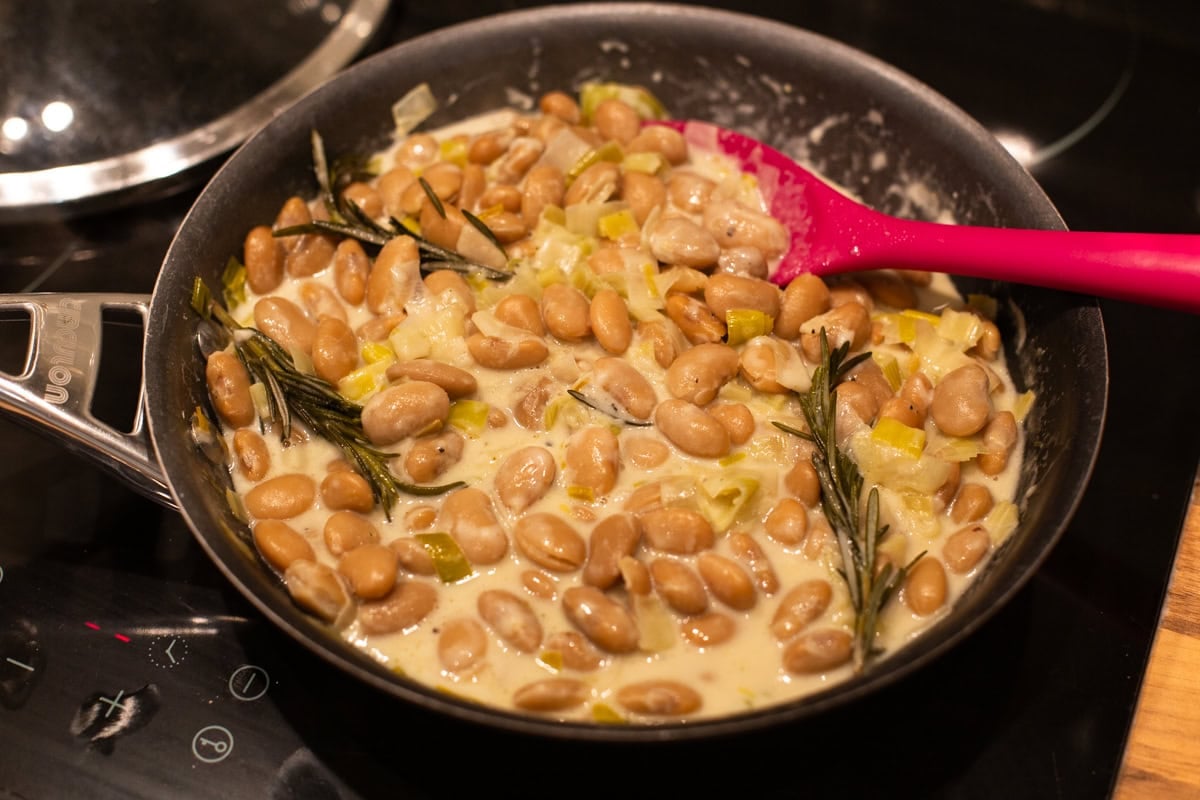 A frying pan with creamy butter beans and leeks.