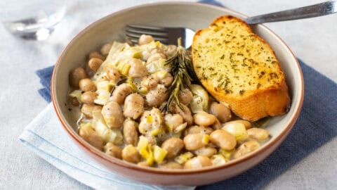 A bowl of creamy butter beans and garlic bread.